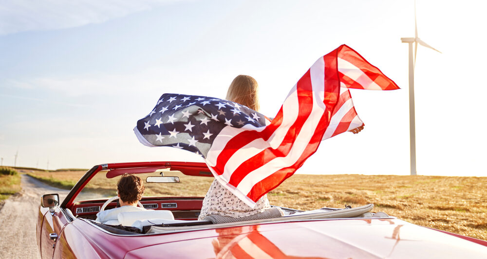 a women holding a flag driving down the road in the USA