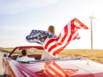 a women holding a flag driving down the road in the USA