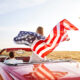 a women holding a flag driving down the road in the USA