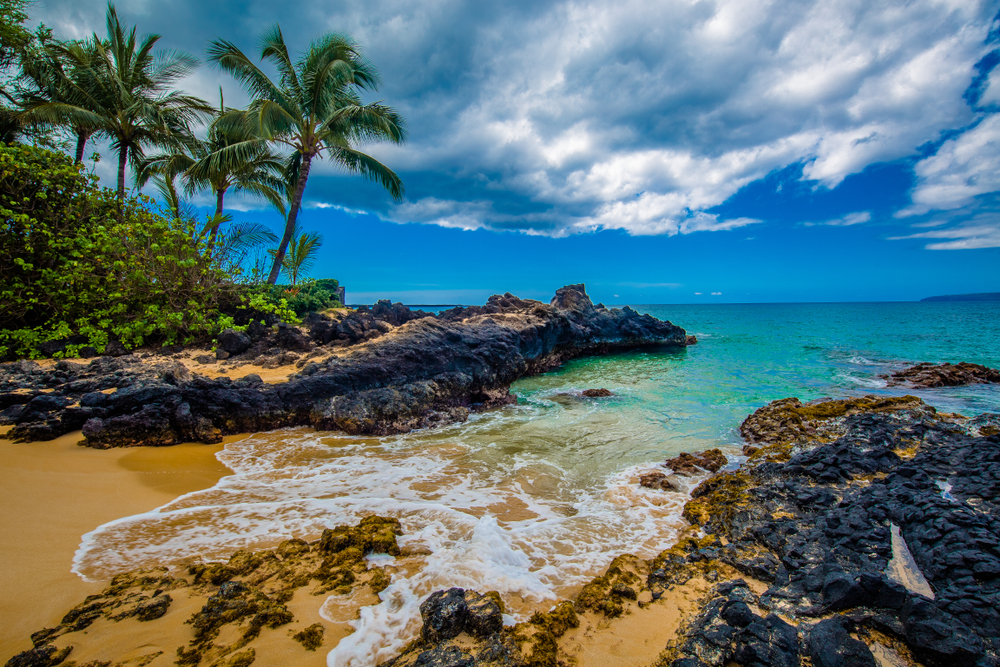 one of the beaches in maui hawaii with black rocks and beautiful water 