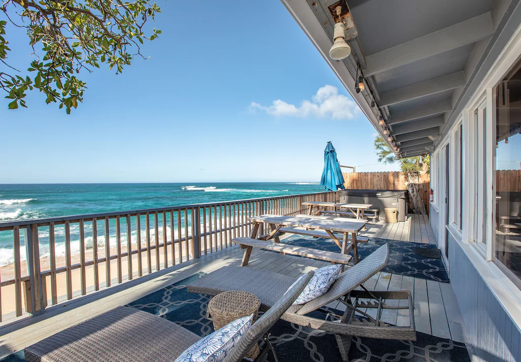 View of the deck and sparkling turquoise water at this beach house for rent in Oahu 