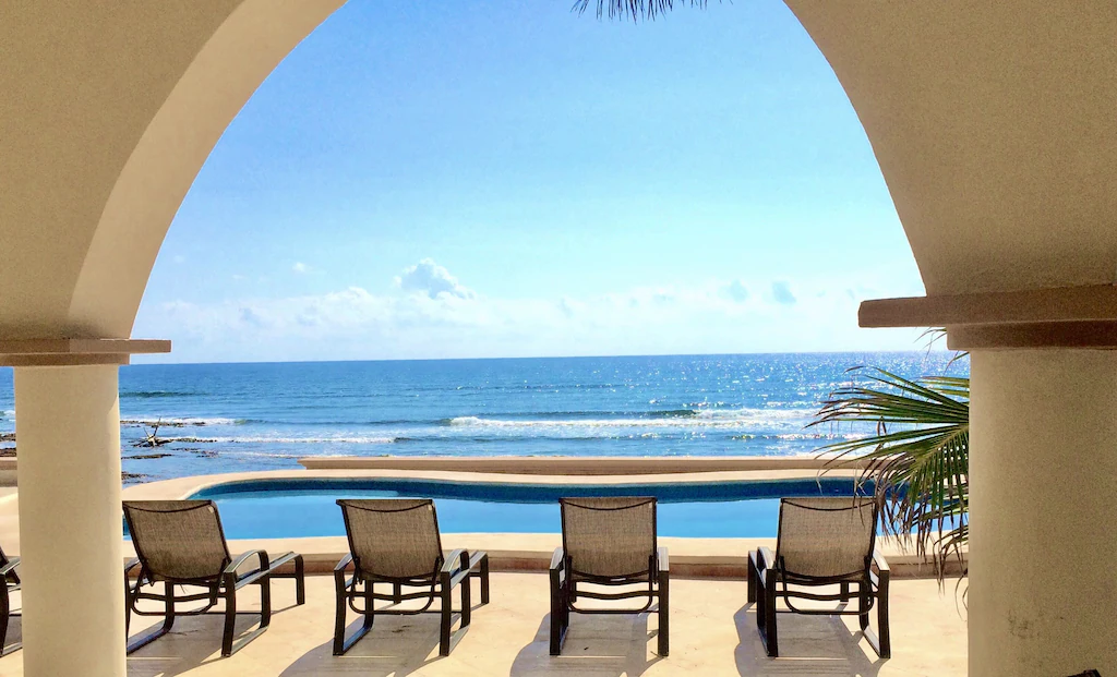 View of the lounge chairs, pool and ocean beyond off the back deck of the Oceanfront Villa, a Tulum VRBO