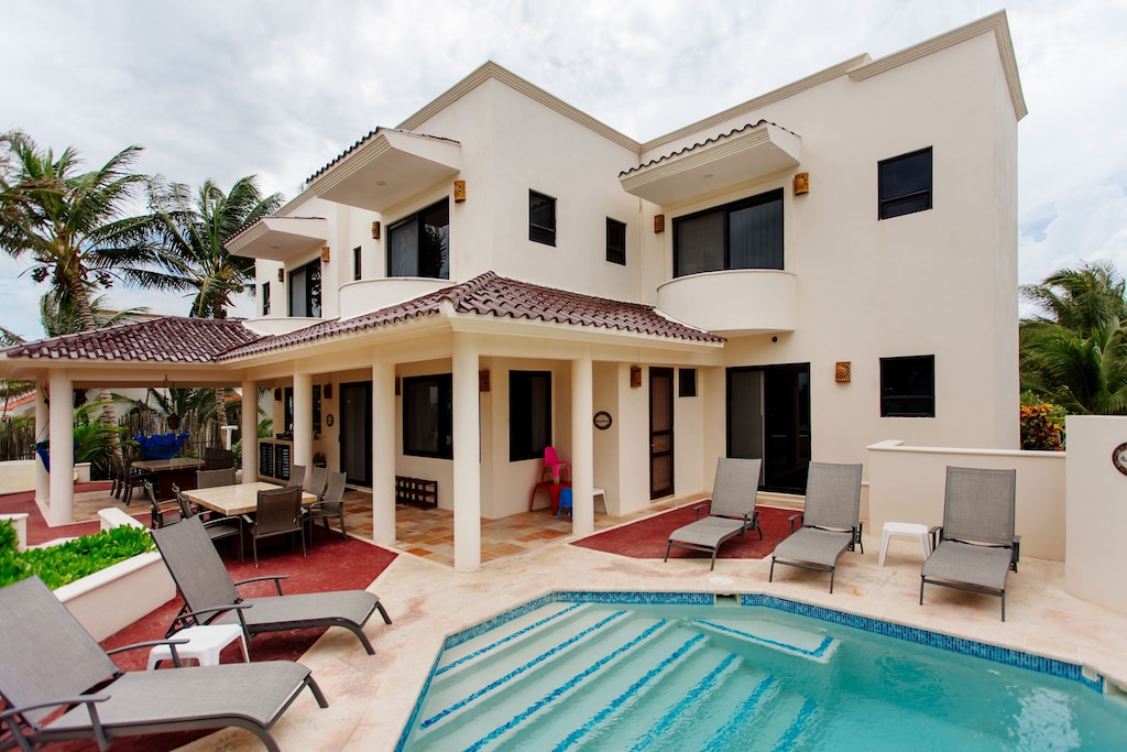 View of the pool, patio area, and red tiled roof of the Chef Included Villa