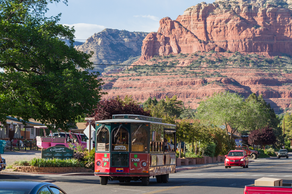 Trolley giving a tour of the city and scenery. There are mountains in the background and you can see the uptown area. 