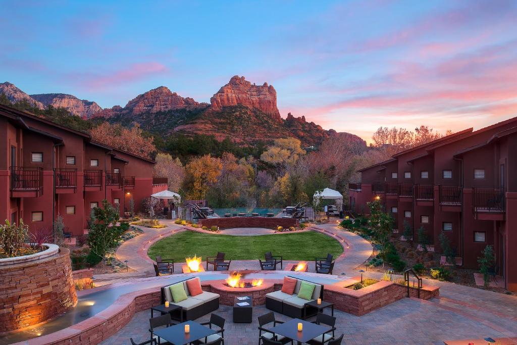 Hotel outside space with firepit and green area. Rooms are off to the side and mountains are in the distance.  