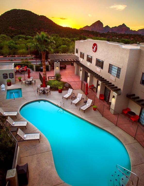 Picture of hotel pool surrounded by hotel rooms. The pool has chairs around it and there is a hot tub above the pool. 