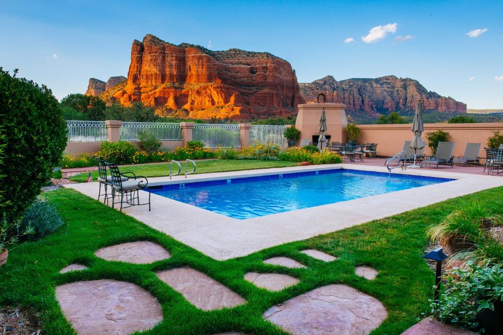 Pool surrounded by grass and a balcony looking over the red mountains.  