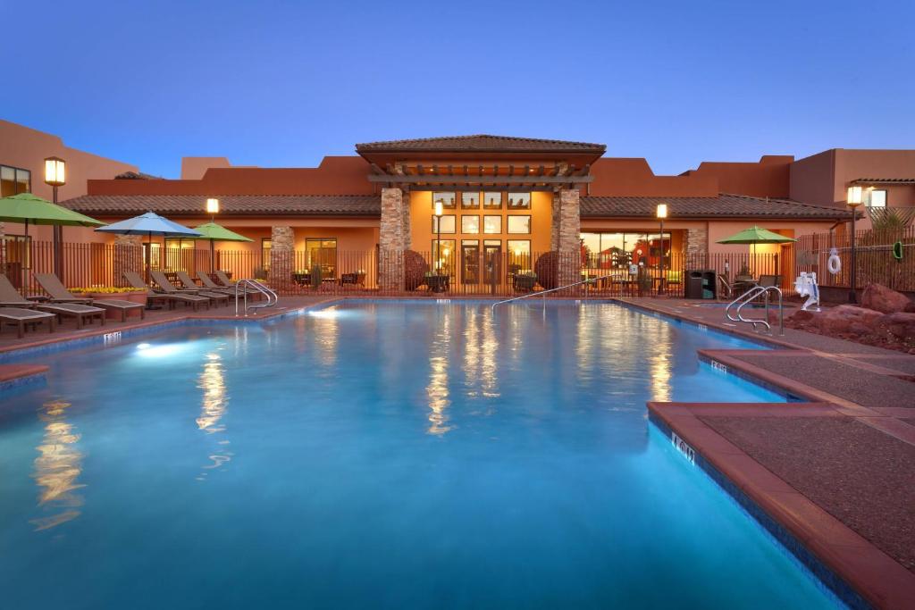 Huge hotel pool lit at night with hotel in the background. 