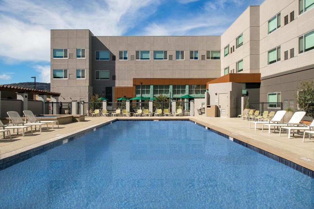 Hotel pool surrounded by chairs and hotel rooms. 