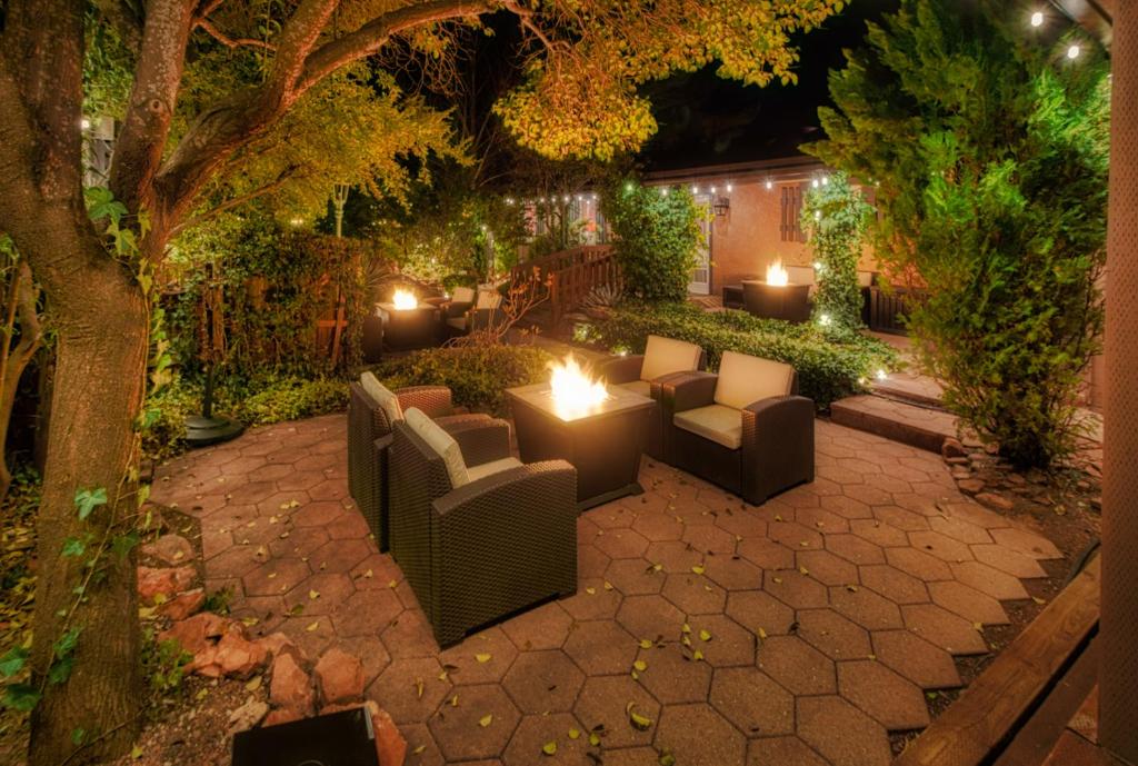 Hotel garden with chairs and a table surrounded by trees. There is a firepit between the chairs. 