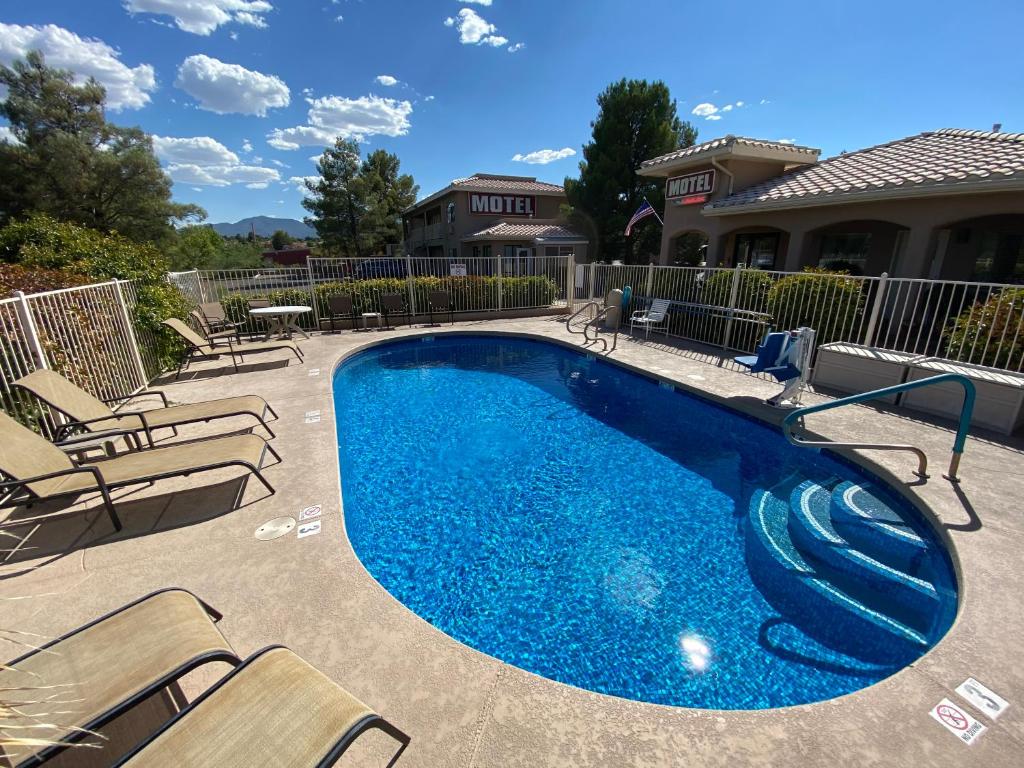 Hotel pool with chairs around and hotel rooms in the background