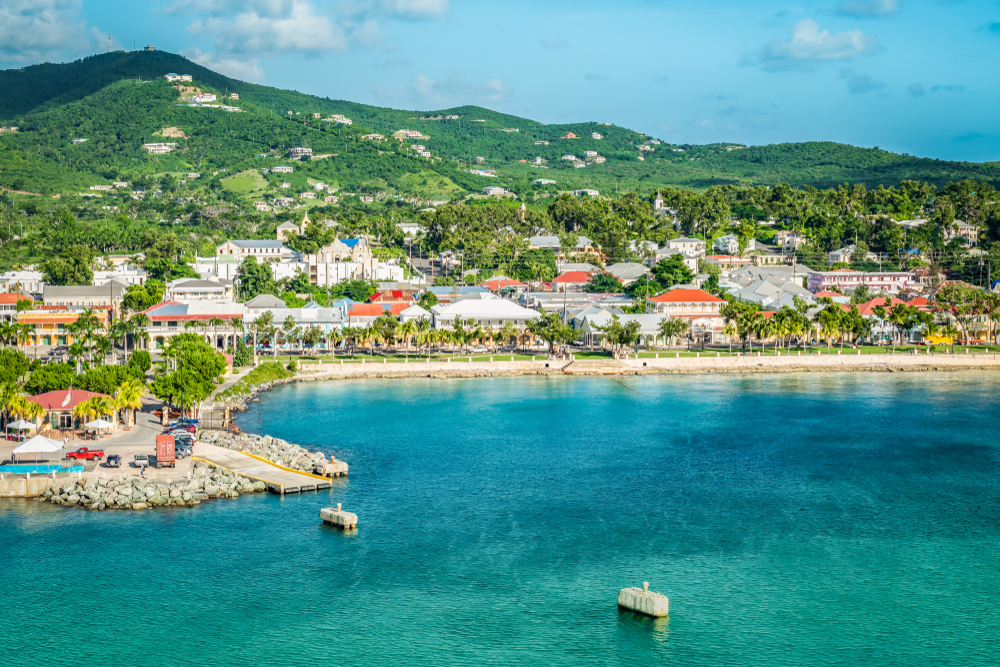the beautiful island of st. Croix in the winter time. The water is a light blue color and there are cute beach bungalows below the big green mountain ranges. visiting here is one of the best winter vacations in the USA