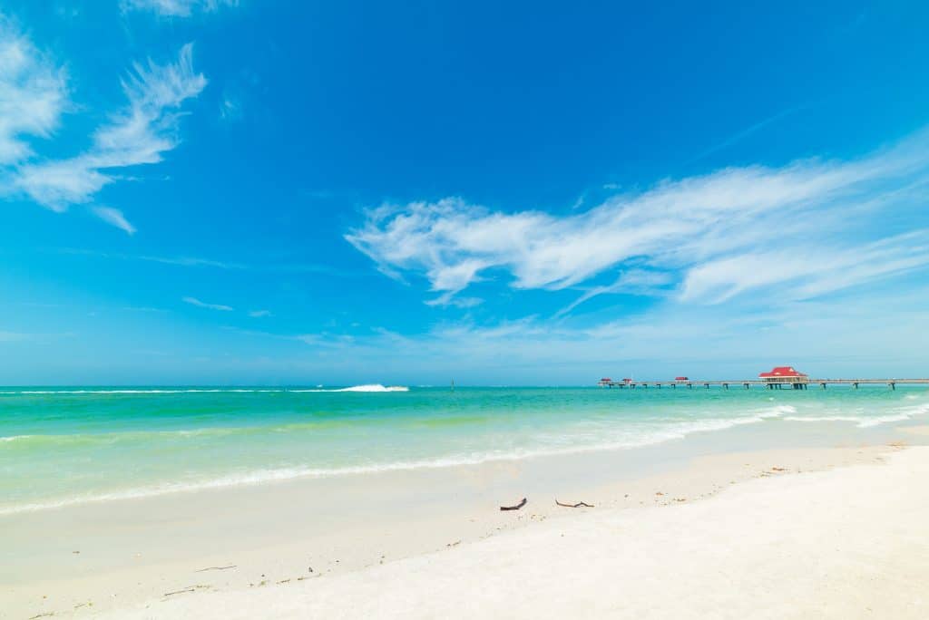 Clearwater beach with white sugary sand and emerald water with the pier in the background on a sunny day