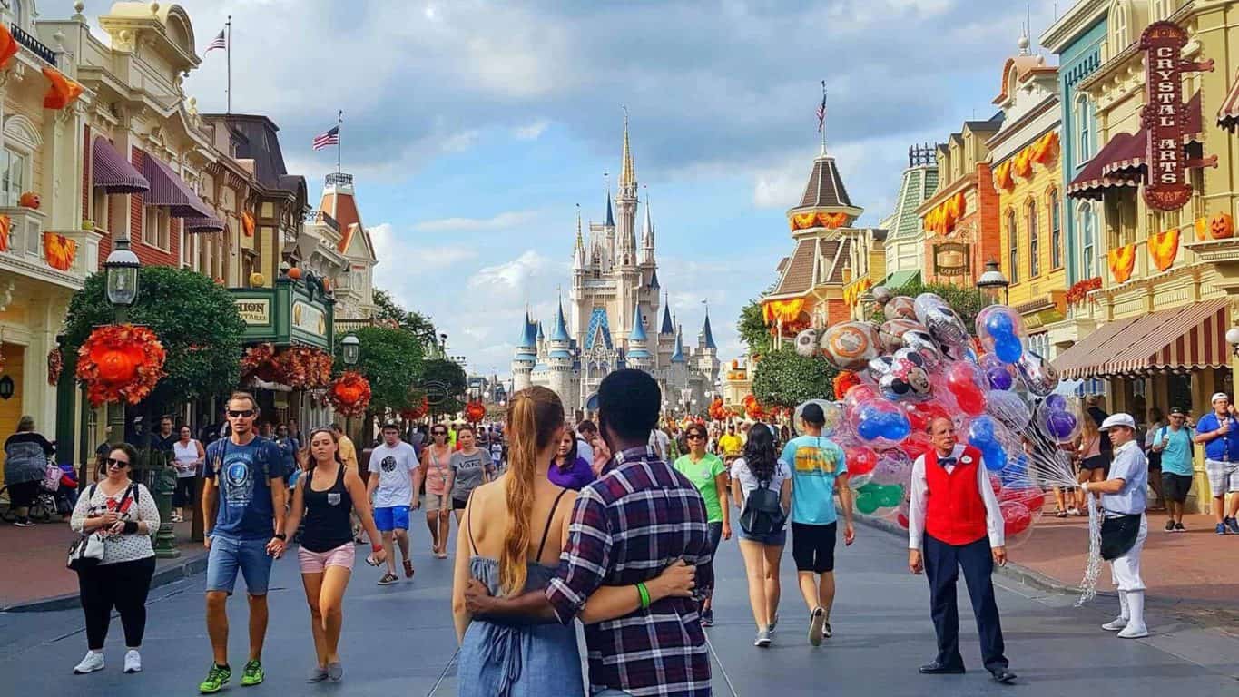 The backs of a couple with arms around each other posing on main street in front of Cindarellas Castle at the Magic Kingdom