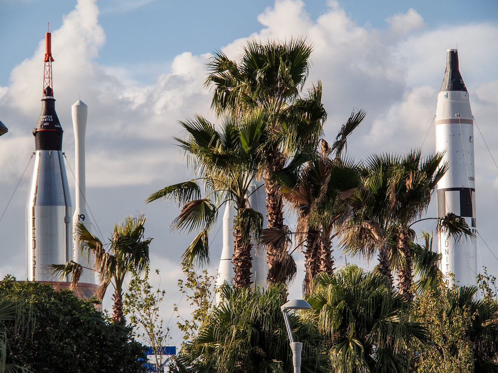 Three rockets standing up at Kennedy Space Center Garden with palm trees