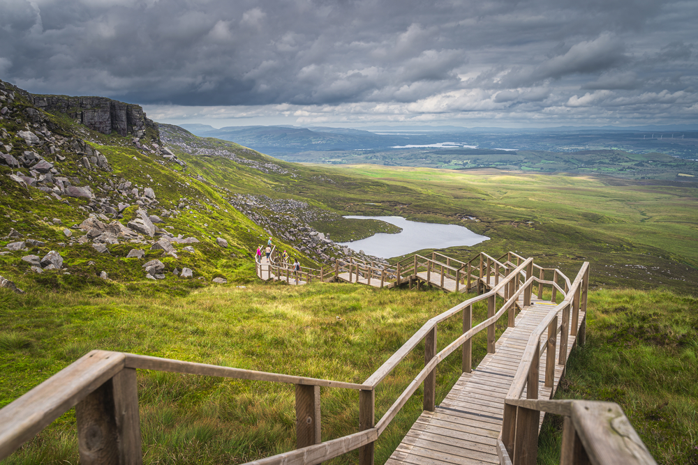View looking down the boardwalk stairs of Cuilcagh Boardwalk Trail with views for miles on a cloudy day.