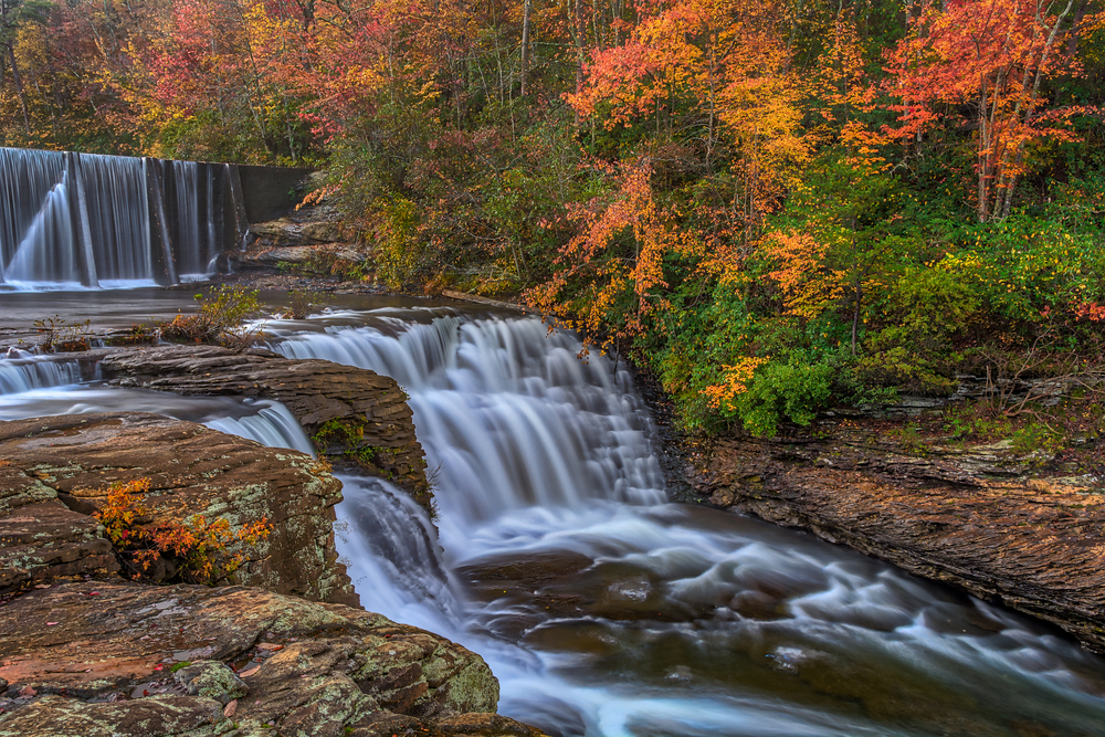Tiered waterfall on a river nestled in fall foliage.