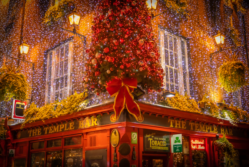 Temple bar in Christimas season. The pub is covered in small lights and has a huge tree on the side. 