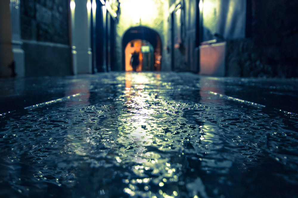 Focus on wet ground along dark medieval alley on a rainy night, Butter Slip, Kilkenny Ireland. The article is about the best time to visit Ireland 