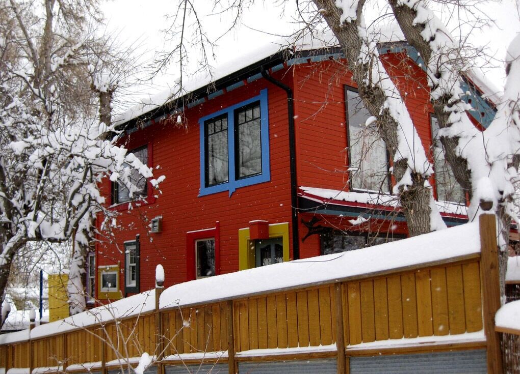 cheery red exterior of the colorful artists apartment in the snow