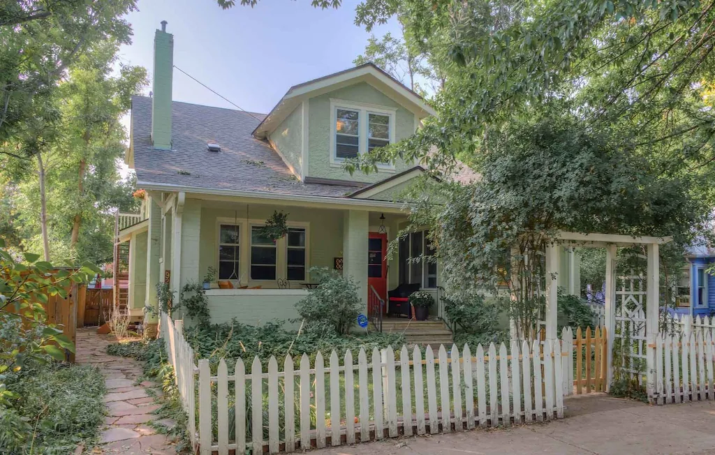 view of the green painted exterior and lush garden of the Downtown Delight, one of the best airbnbs in Boulder 