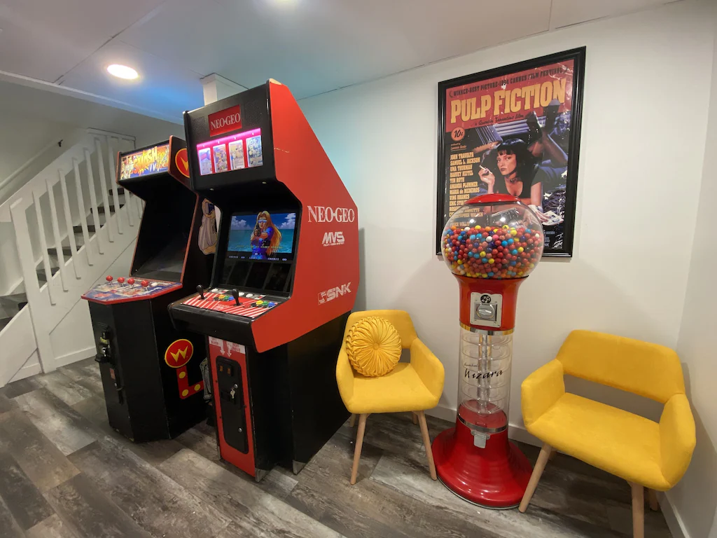 View of the arcade games, two bright yellow chairs, and the gumball machine of the Boulder Farm Arcade. 