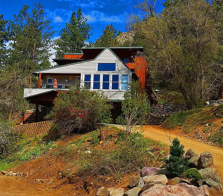View of the creekside craftsman Boulder vrbo surrounded by trees. 