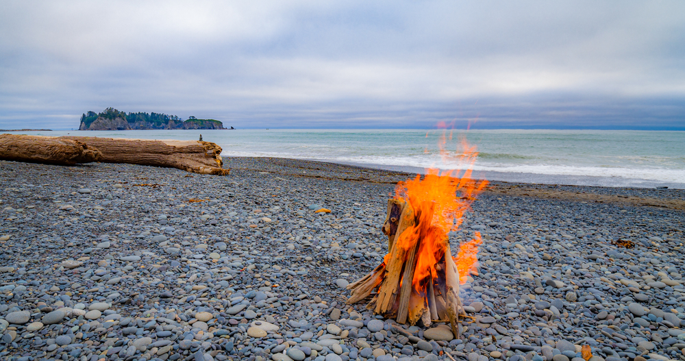 A fire on rocky terrain burns at one of the top locations in Oregon for the best beach camping in the USA. 
