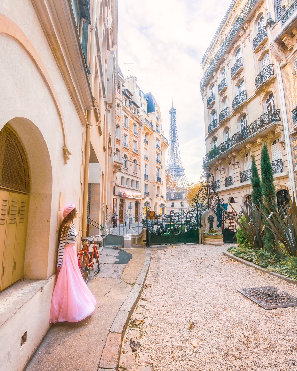 Woman in pink skirt and beret stands in Avenue Rapp with views of the Eiffel Tower.