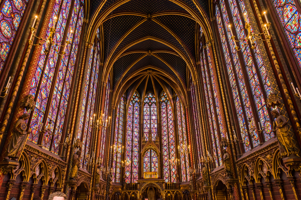 Inside Sainte-Chapelle with high ceilings and stained glass windows.