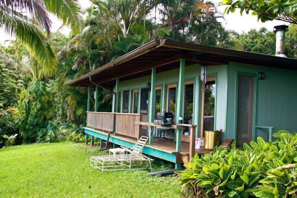 View of the exterior of the Tropical Garden Cottage with its spacious front porch and surrounding lush greenery 