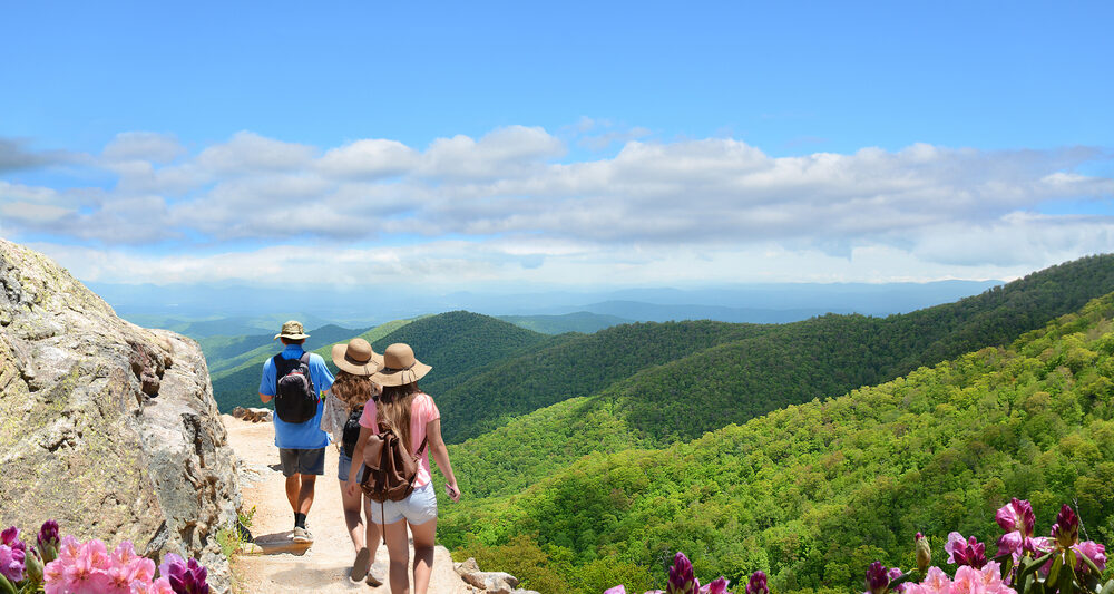 people hiking in asheville north carolina with blue skies and green mountains