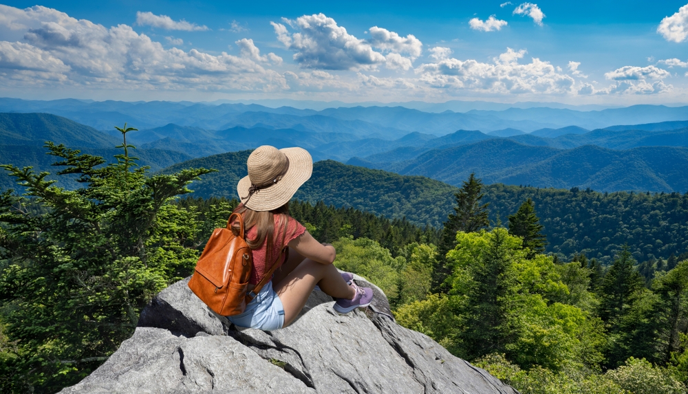 a girl sitting on the rocks in Asheville over looking the blue ridge 