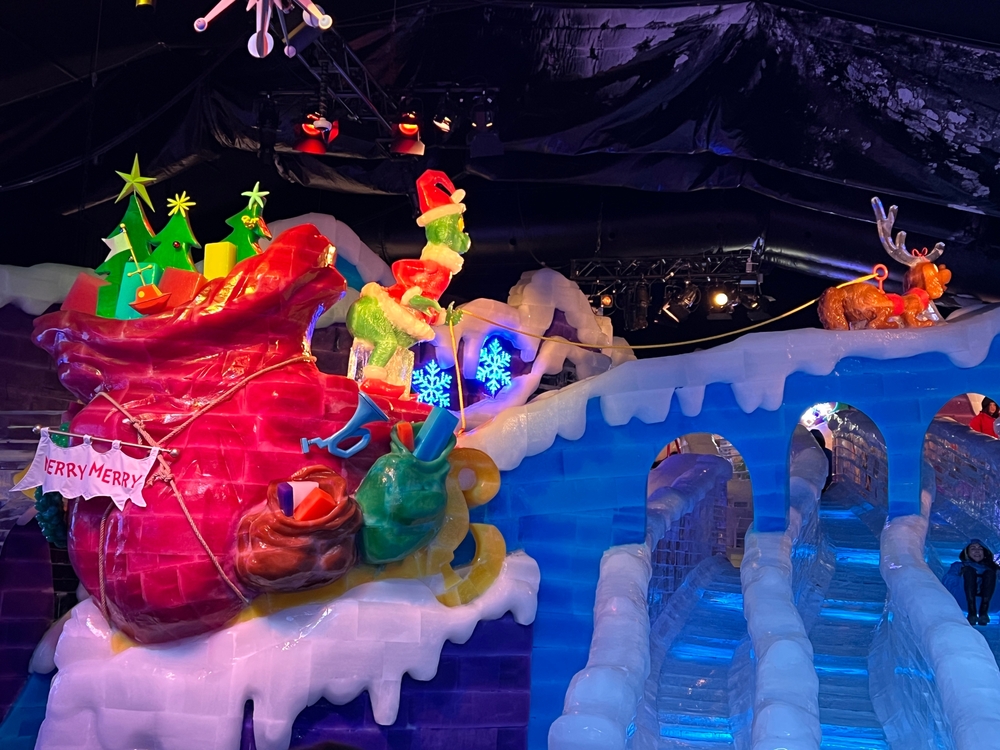 colourful ice sculptures of a scene from the cartoon grinch with his sack full of toys and max tugging them along!