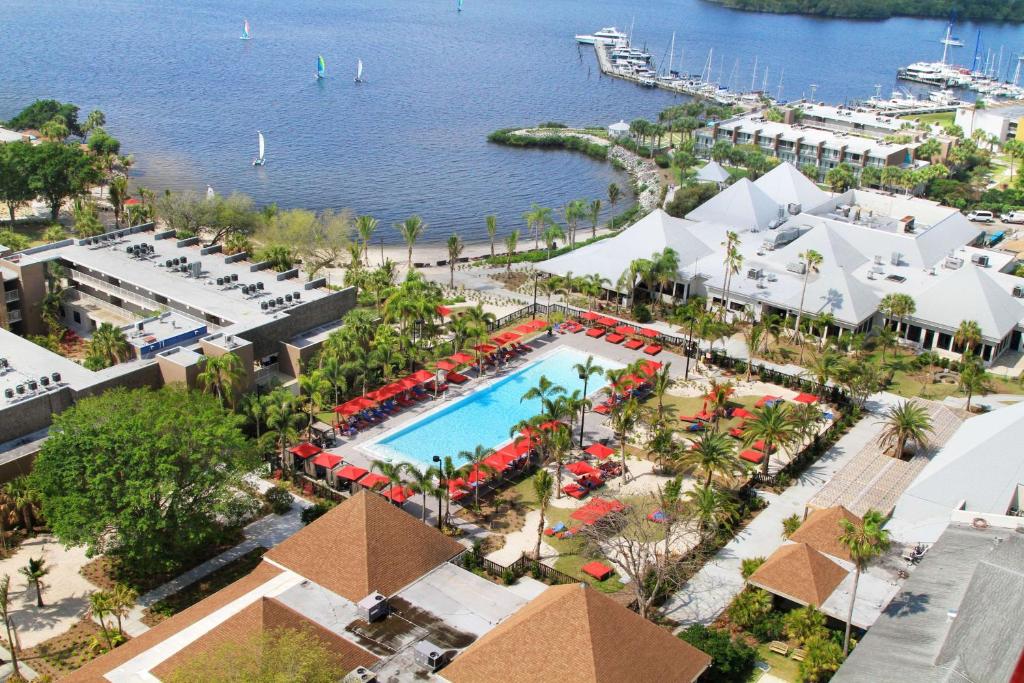 Drone shot of the resort showing the pool, the bay and all the amenties. There are red umberellas. 