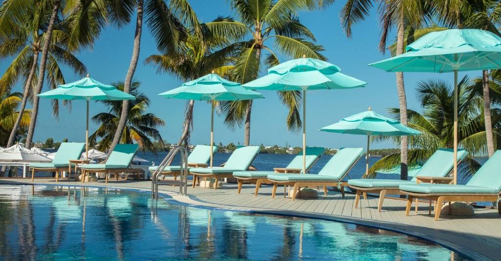 blue beach chairs and blue umbrellas lined up along a pool with a blue sky at an all inclusive resort in the South USA