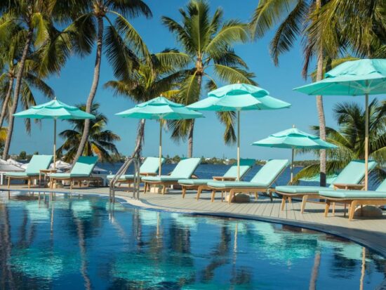 blue beach chairs and blue umbrellas lined up along a pool with a blue sky at an all inclusive resort in the South USA