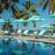 blue beach chairs and blue umbrellas lined up along a pool with a blue sky at an all inclusive resort in the South USA