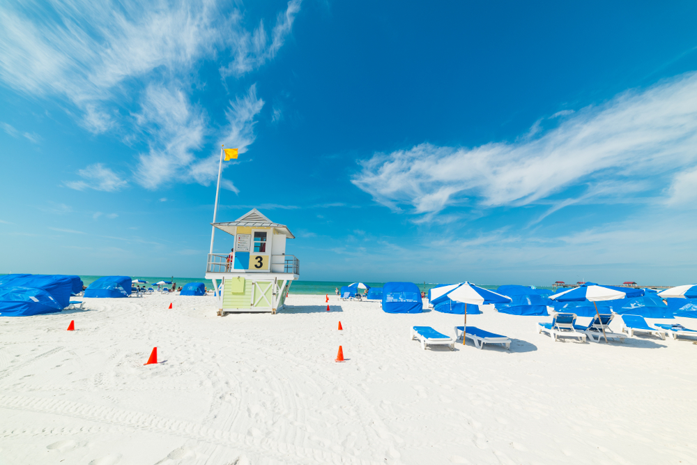 Beach chairs, umbrellas, and a lifeguard stand line the white sand beaches in Tampa FL. 