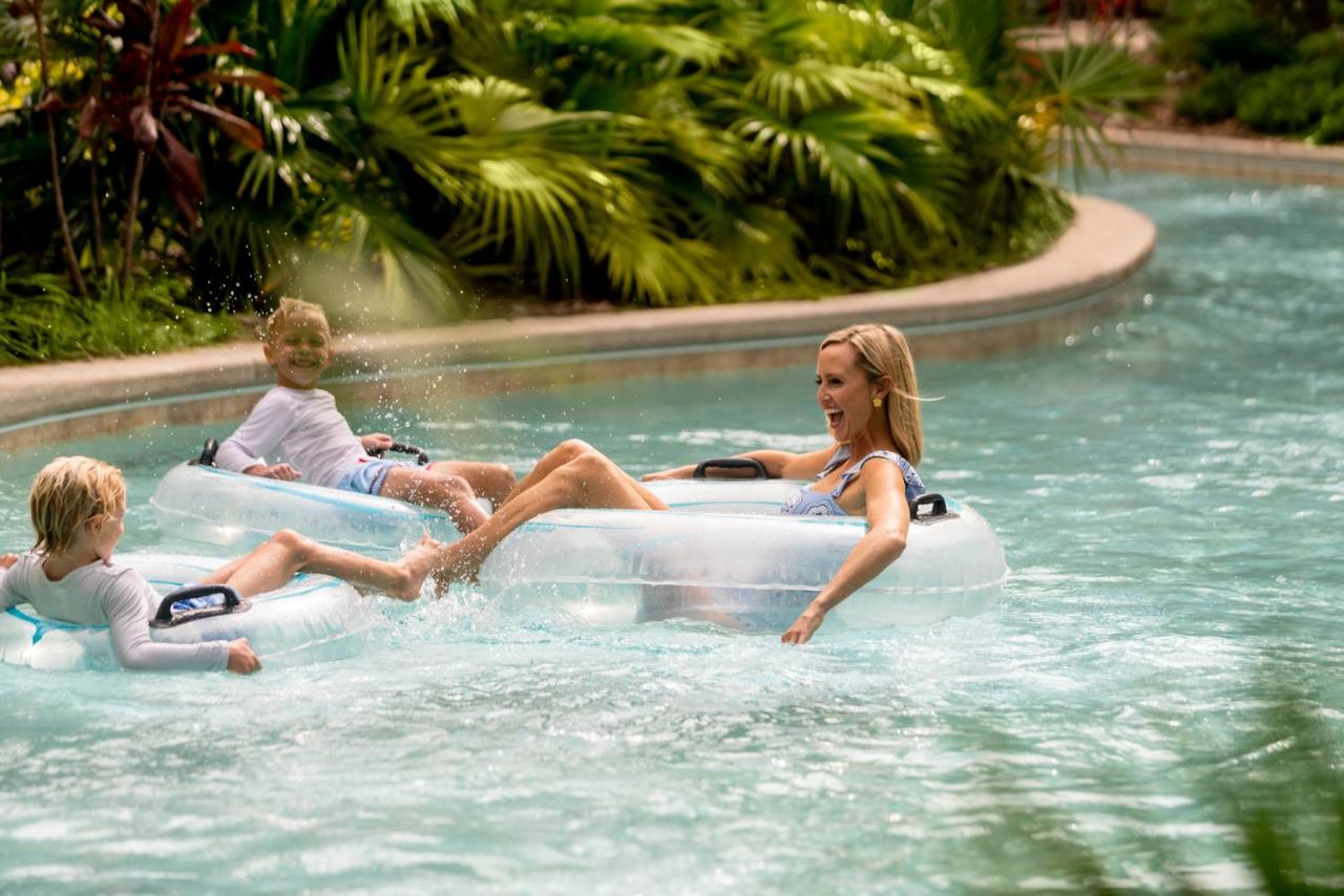 A mom and her two children floating down the lazy river in inter tubes surrounded by lush foliage at one of the best resorts in Florida with water parks for those looking for luxury