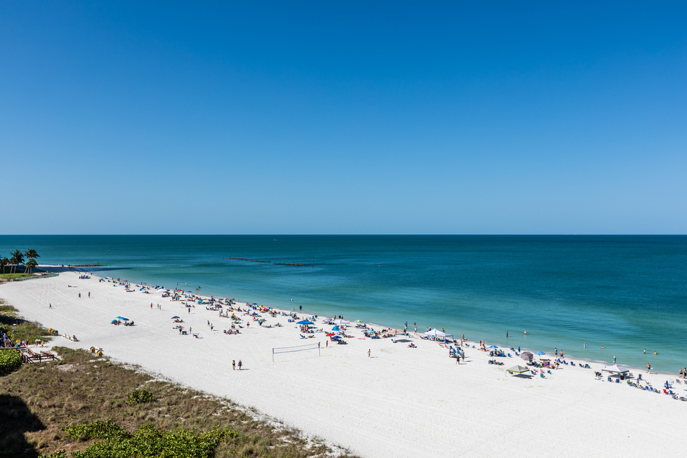 light teal and dark blue waters, clear sky and bright white sand beaches with plenty of people enjoying the weather!