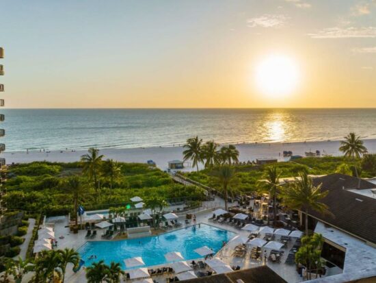 sunset with a pool and ocean in the background at one of the best beachfront resorts at marco island florida