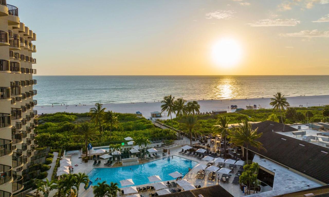 a dusky sky with bright green trees, a beautiful pool area and big palm trees overlooking a beautiful white sand beach! 