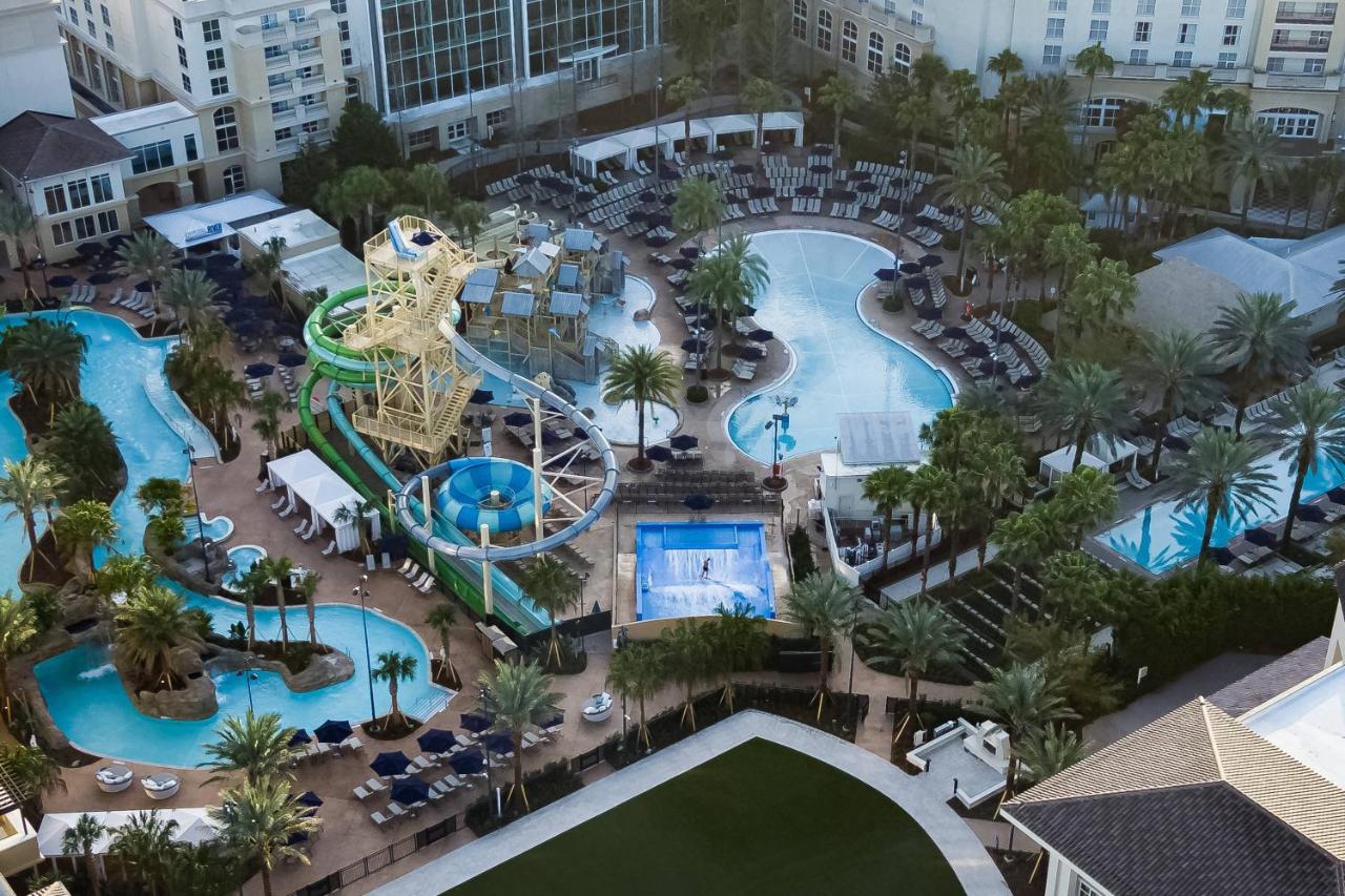 aerial photo of water park, swimming pool, outdoor seating, and palm trees near a resort 
