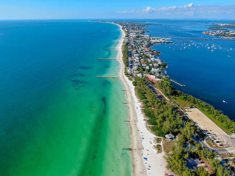 dark blue waters going into green shorelines, with beautiful white sand, tons of greenery and houses going along an isle of one of the best small towns in Florida!