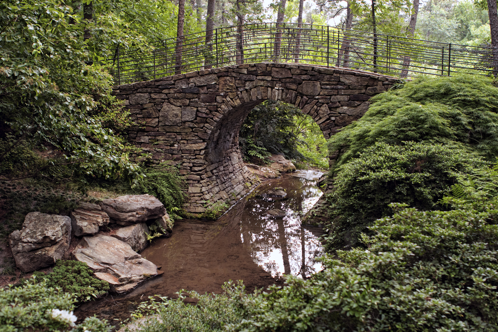 Stone walking bridge over a creek in Garvan Woodland Gardens, one of the best things to do in Arkansas. 
