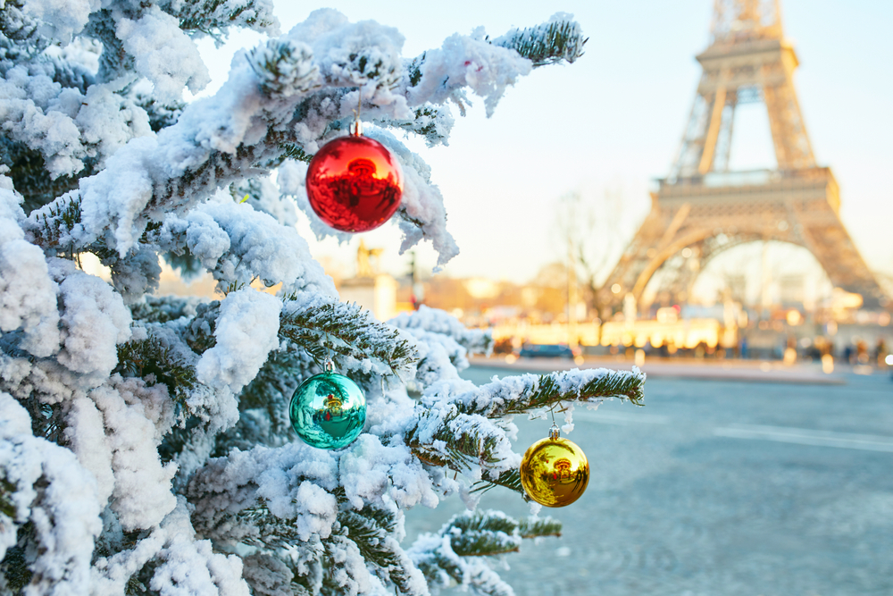 Christmas tree covered with snow and decorated with red, green and yellow balls, Eiffel tower in the background. Season holidays in Paris, France