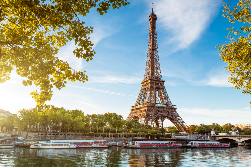 Eiffel Tower by the river with boats outside. The article is about the best time to visit Paris.