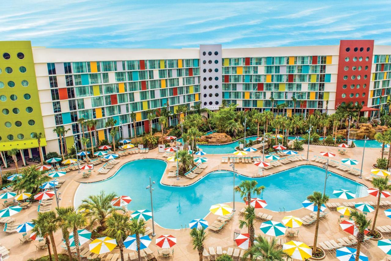 pool with curvy edges in front of a retro style resort, lazy river is there as well with palm trees around it 