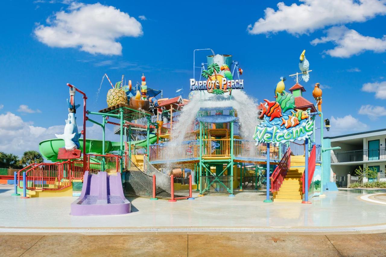 a water play ground with a large water bucket on the top, stairs on both sides, many water slides coming off the play ground on a bright day with clouds in the sky , one of the best hotels with water parks in orlando. 